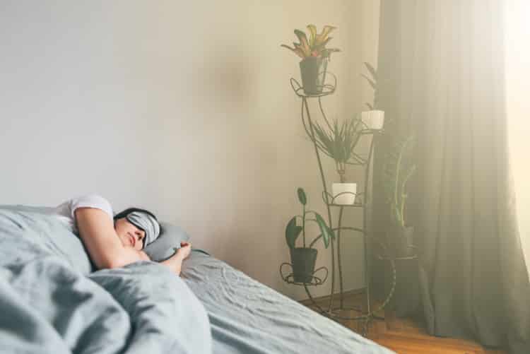 Woman sleeping late with eye covers and light streaming into room