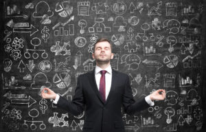 Businessman meditating in front of chalkboard with complex illustrations