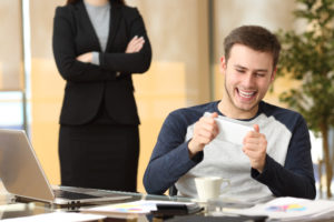 Procrastinating office worker playing on phone in front of boss