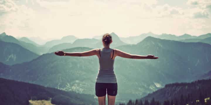 fit woman enjoying reaching mountain summit